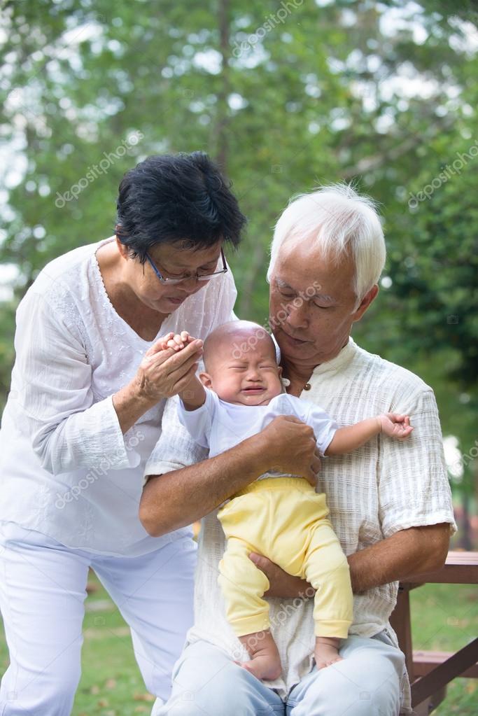Asian grandparents comforting crying baby