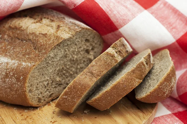Pão parcialmente fatiado na toalha — Fotografia de Stock
