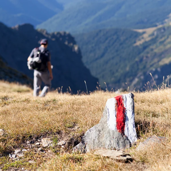 Jovem caminhando por um caminho marcado nas montanhas — Fotografia de Stock