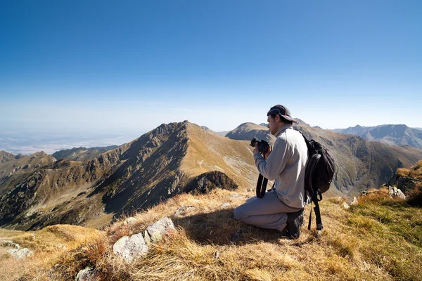 Joven senderismo y tomar fotos desde la cima de las montañas — Foto de Stock