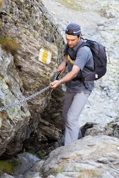 Young man hiking on difficult mountain trail — Stock Photo, Image