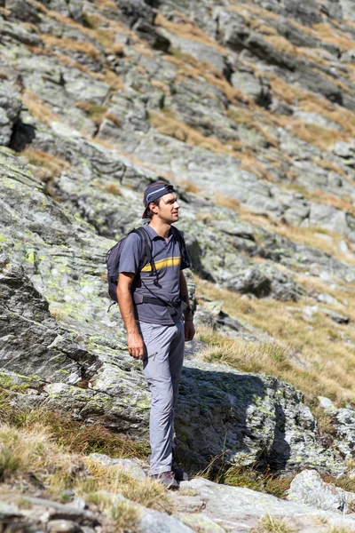 Jovem de pé nas montanhas apreciando a vista — Fotografia de Stock
