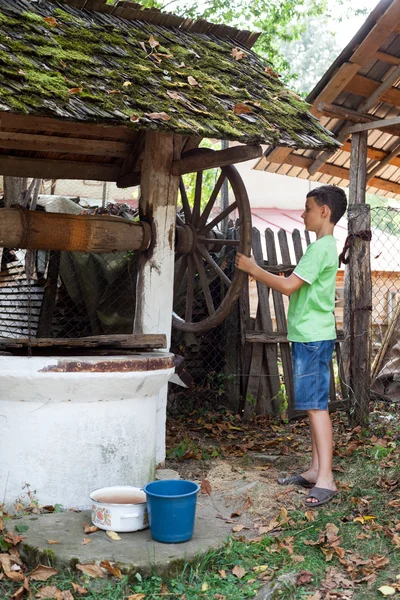 Školák získávání vody ze studny — Stock fotografie