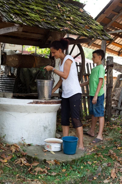 Madre e figlio ottenere acqua dal pozzo — Foto Stock