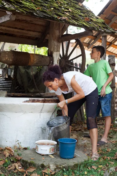 Mother and son getting water from well — Stock Photo, Image
