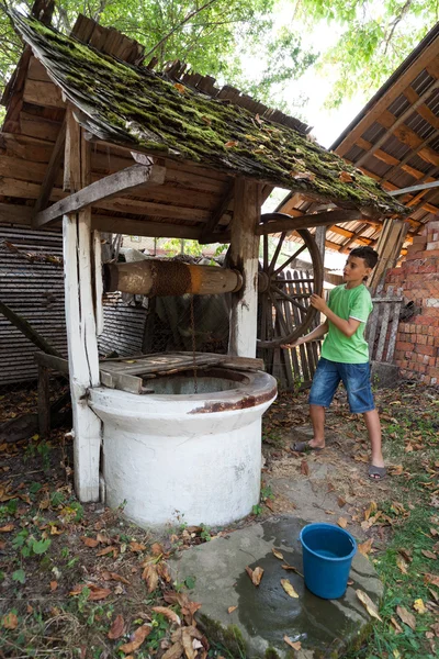 Skolpojke att få vatten från brunn — Stockfoto