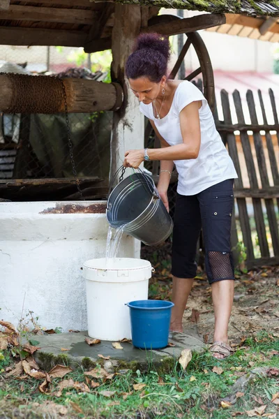 Woman getting water from well — Stockfoto