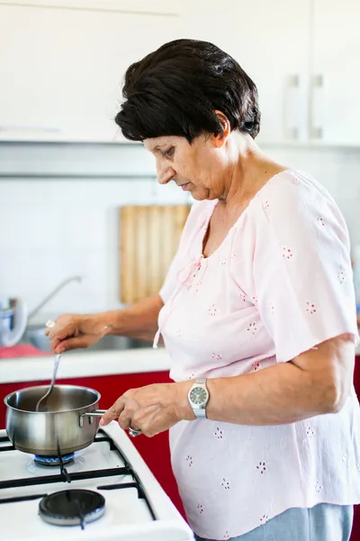 Seniorin bereitet Essen zu — Stockfoto