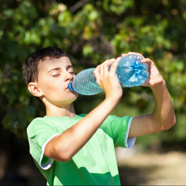 Милый мальчик пьет воду из бутылки — стоковое фото