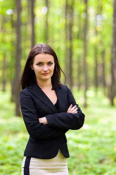 Young businesswoman standing with crossed arms in the woods — Stock Photo, Image