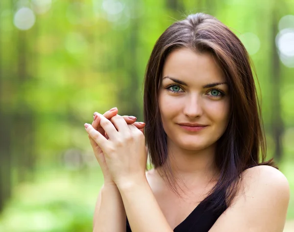 Mulher linda olhando com as mãos perto do rosto na floresta — Fotografia de Stock