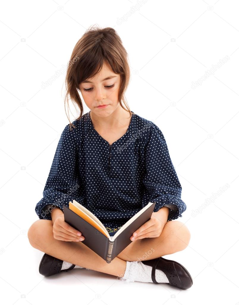 Little girl reading while sitting with crossed legs
