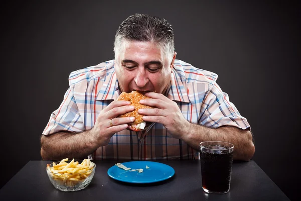 欲の深い男食べるハンバーガー — ストック写真