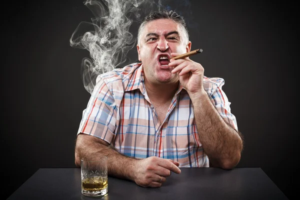 Зрелый мафиози пьет и курит, сидя за столом. — стоковое фото