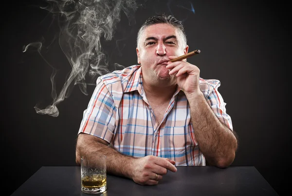 Mature mafia man drinking and smoking while sitting at table — Stock Photo, Image