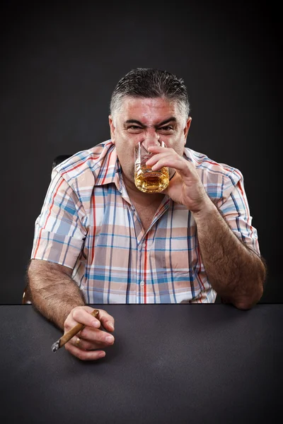 Mature mafia man drinking and smoking while sitting at table — Stock Photo, Image