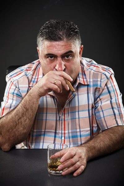 Mature mafia man drinking and smoking while sitting at table — Stock Photo, Image