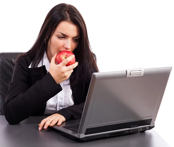 Ofis masa başında otururken bir elma yemek genç iş kadını — Stok fotoğraf