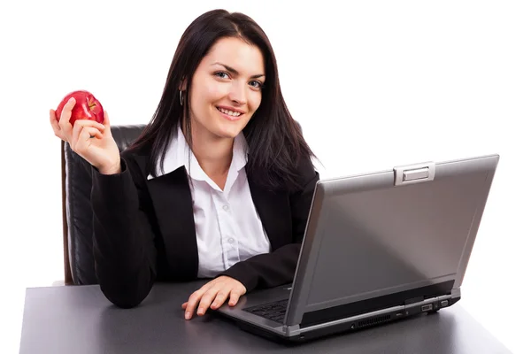 Young businesswoman eating an apple while sitting at office desk — Stock Photo, Image