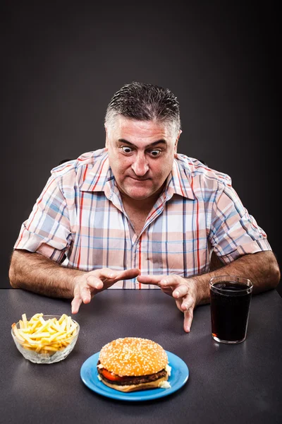 Homem ganancioso olhando para hambúrguer Imagem De Stock