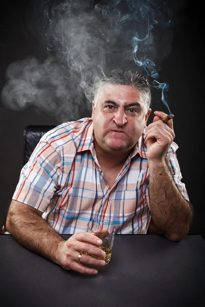 Ώριμη μαφία άνθρωπος κατανάλωση και το κάπνισμα ενώ κάθεται στο τραπέζι Εικόνα Αρχείου