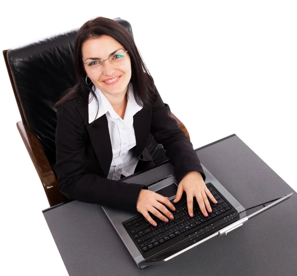 Happy young businesswoman working on laptop while sitting in an Stock Picture