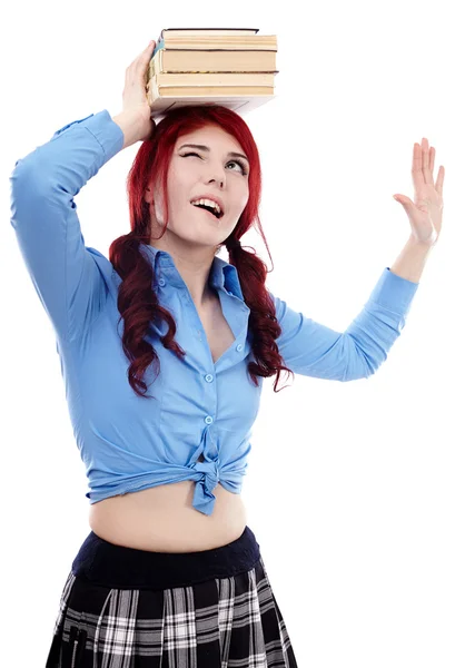 Jonge schoolgirl balancing een stapel boeken op haar hoofd — Stockfoto