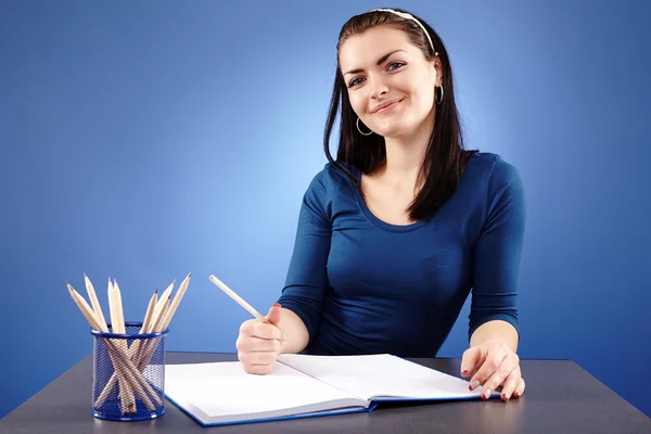 Lächelnde Studentin sitzt an ihrem Schreibtisch — Stockfoto