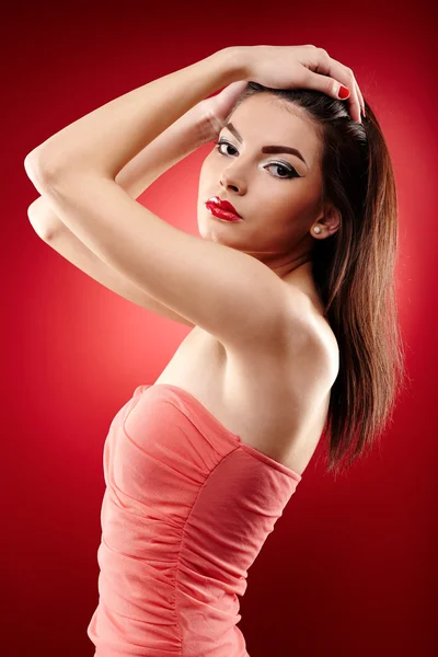 Beautiful brunette posing on red background — Stock Photo, Image