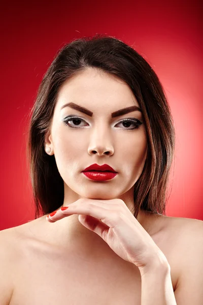 Mooie glamour brunette op rode achtergrond — Stockfoto