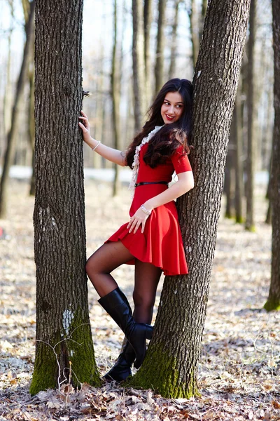 Beautiful woman leaning on a tree trunk — Stock Photo, Image