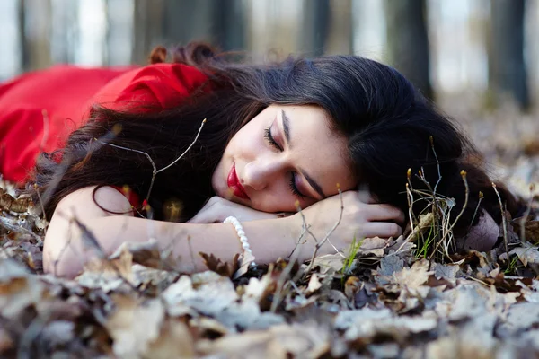 Vacker kvinna som sover på marken i skogen — Stockfoto