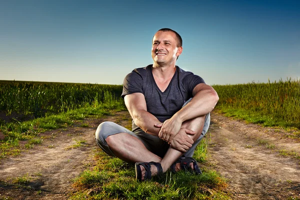 Young man sitting on a country road — Stock Photo, Image