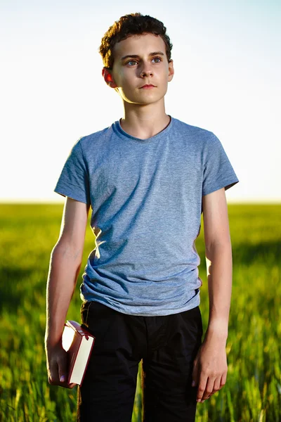 Adolescente com um livro em um campo de trigo — Fotografia de Stock