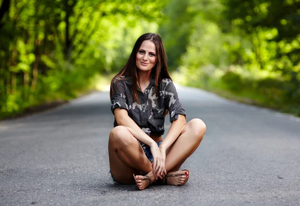 Mulher atraente sentada na estrada — Fotografia de Stock