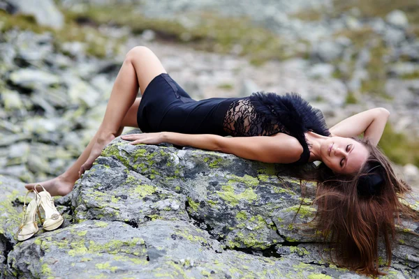 Elegant woman laying on the mountain rocks — Stock Photo, Image
