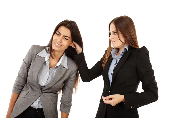 Geschäftsfrau zieht Kollegin am Ohr — Stockfoto