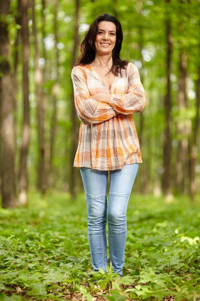 Beautiful woman with arms folded in a forest — Stock Photo, Image