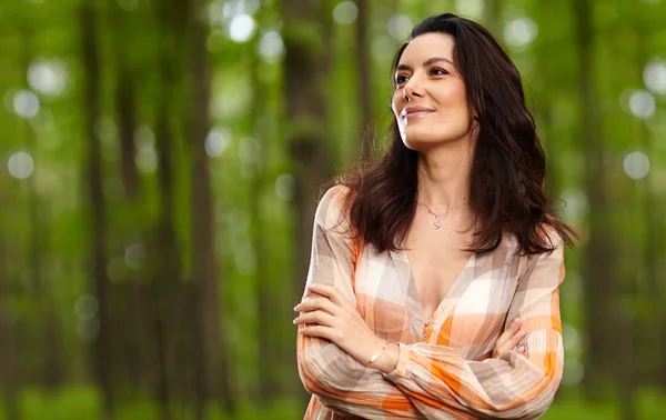 Hermosa mujer con los brazos cruzados en un bosque — Foto de Stock