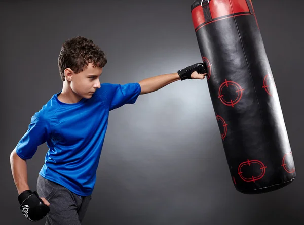 Junge schlägt auf Boxsack ein — Stockfoto