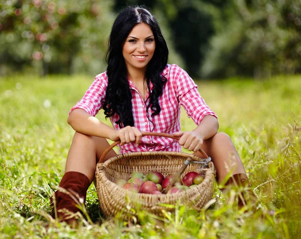 Sexy brunette near a basket of apples — Stock Photo, Image