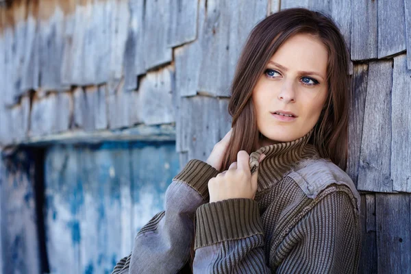 Beautiful woman leaning on a cabin log — Stock Photo, Image