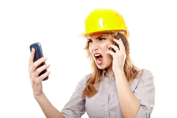 Stressad kvinna ingenjör med två mobiltelefoner och skriker — Stockfoto