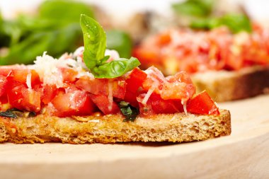 İtalyan domates bruschettas, fesleğen ve parmesan ile dekore edilmiştir.