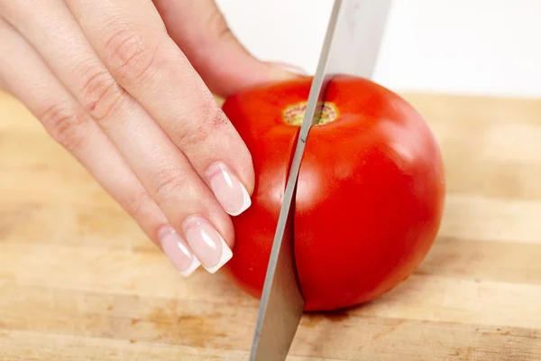 Slicing the tomato on a wooden board — Stock Photo, Image