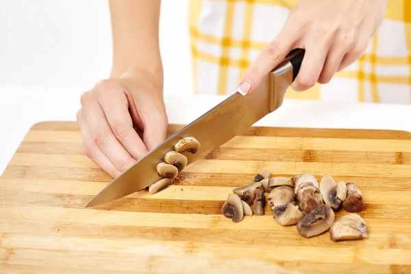 Les mains de cuisinière coupant des champignons sur une planche de bois — Photo