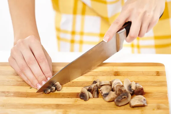 Woman cook's hands chopping mushrooms on a wooden board — Stock Photo, Image