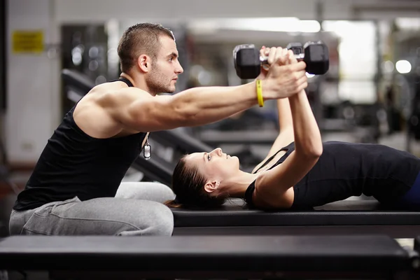 Personlig tränare att hjälpa kvinnan på gym Royaltyfria Stockbilder