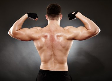Athletic man doing bodybuilding moves for the back muscles clipart