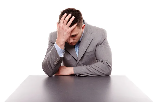 Ongelukkig zakenman zit aan bureau met de hand op het hoofd — Stockfoto